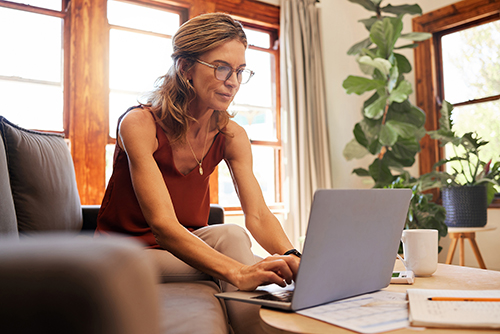middle aged woman sitting in living room on laptop