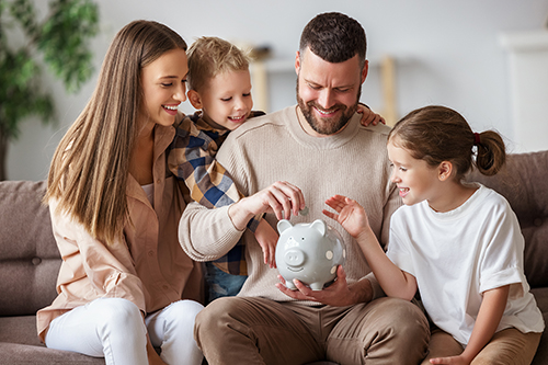 young family putting money into piggy bank